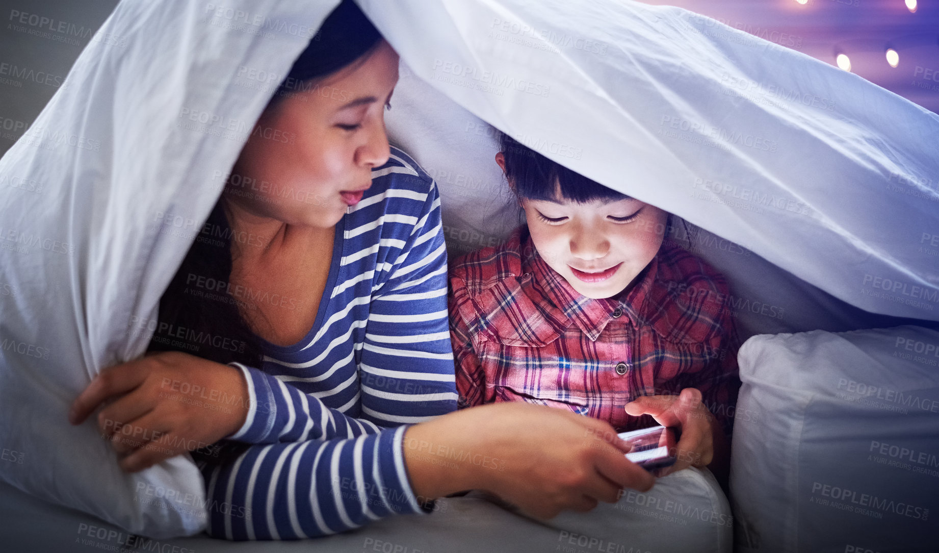 Buy stock photo Cropped shot of an attractive young woman and her daughter using a digital tablet while lying under the covers