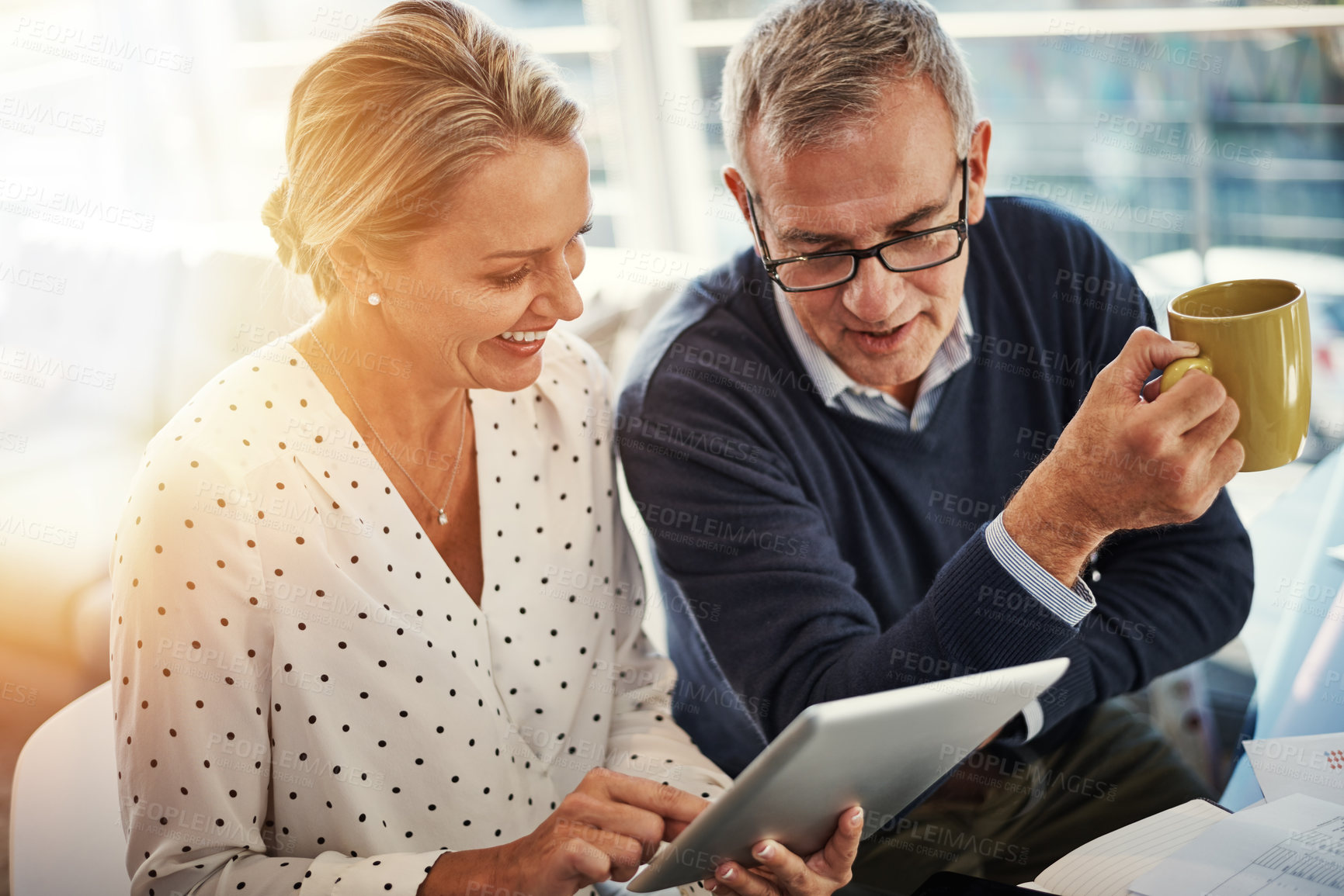 Buy stock photo Shot of a mature couple using a digital tablet while going through paperwork at home