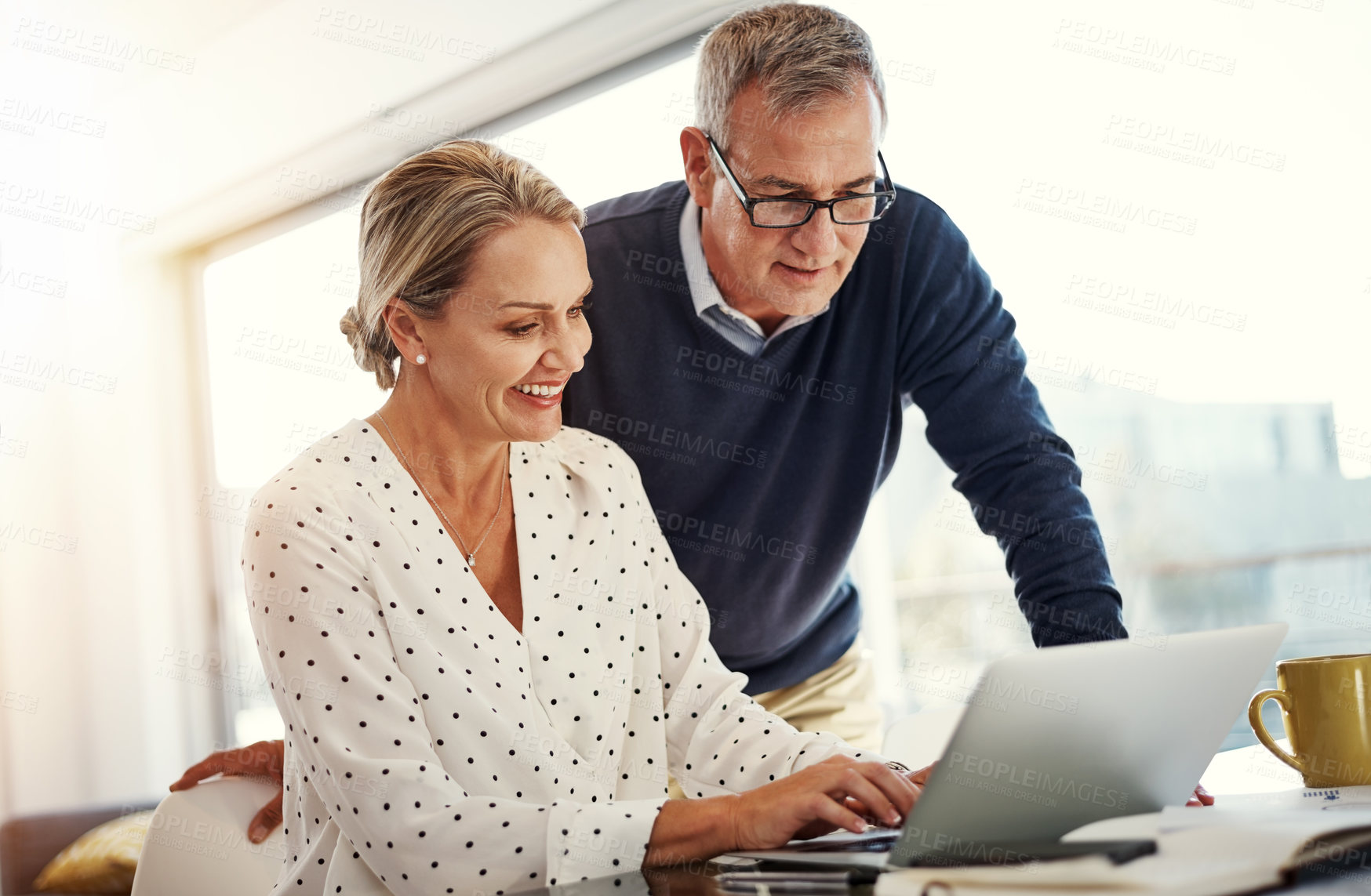 Buy stock photo Shot of a mature couple using a laptop while going through paperwork at home