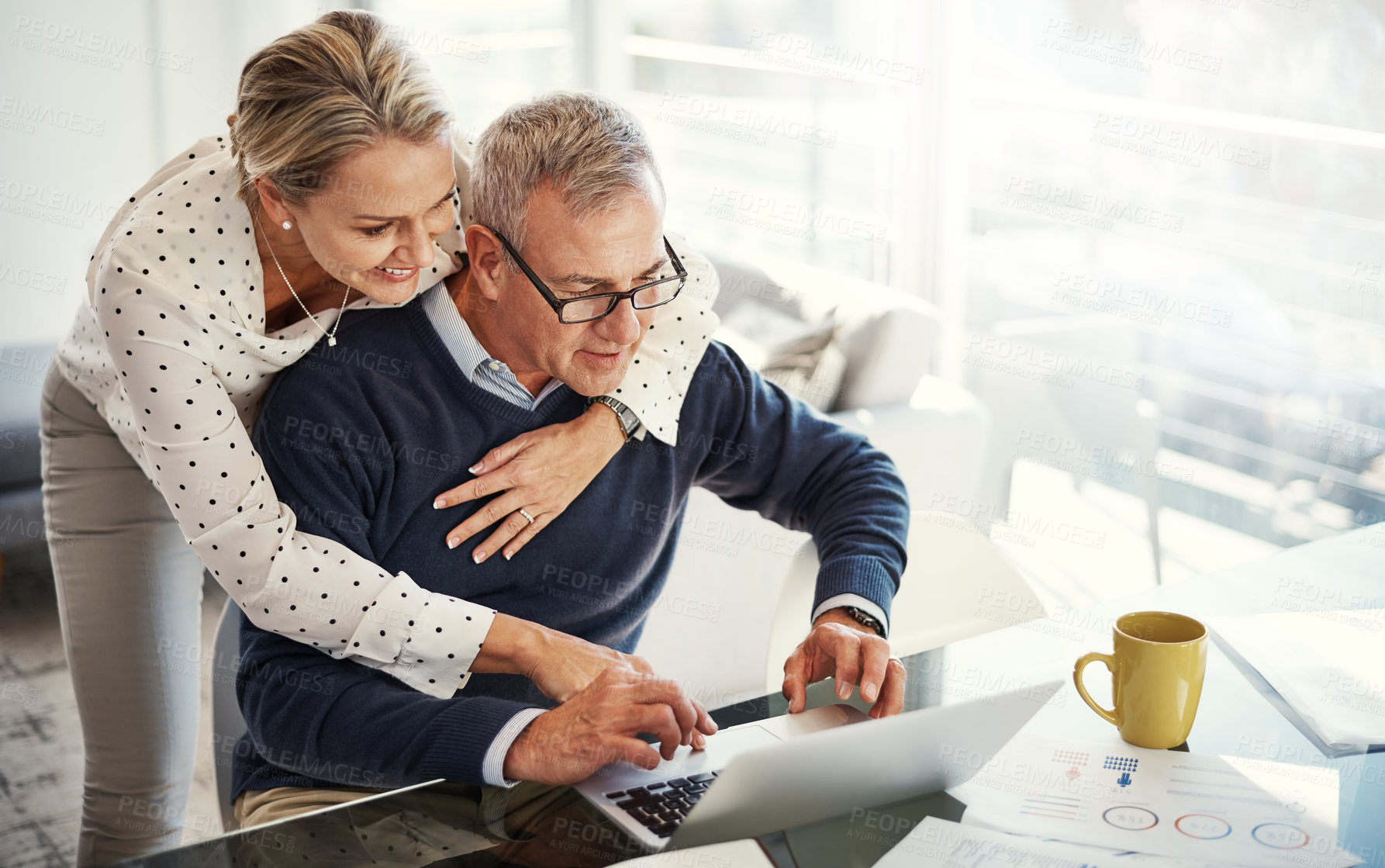 Buy stock photo Shot of a mature couple using a laptop while going through paperwork at home