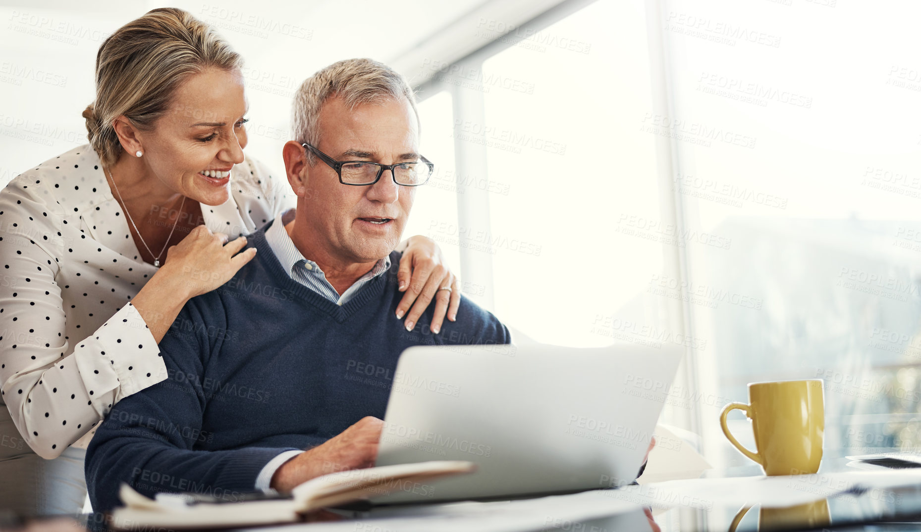 Buy stock photo Shot of a mature couple using a laptop while going through paperwork at home