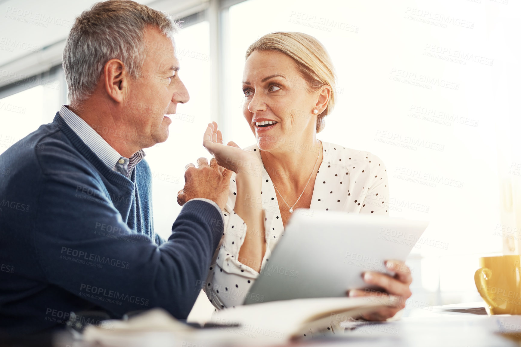 Buy stock photo Shot of a mature couple using a digital tablet while going through paperwork at home