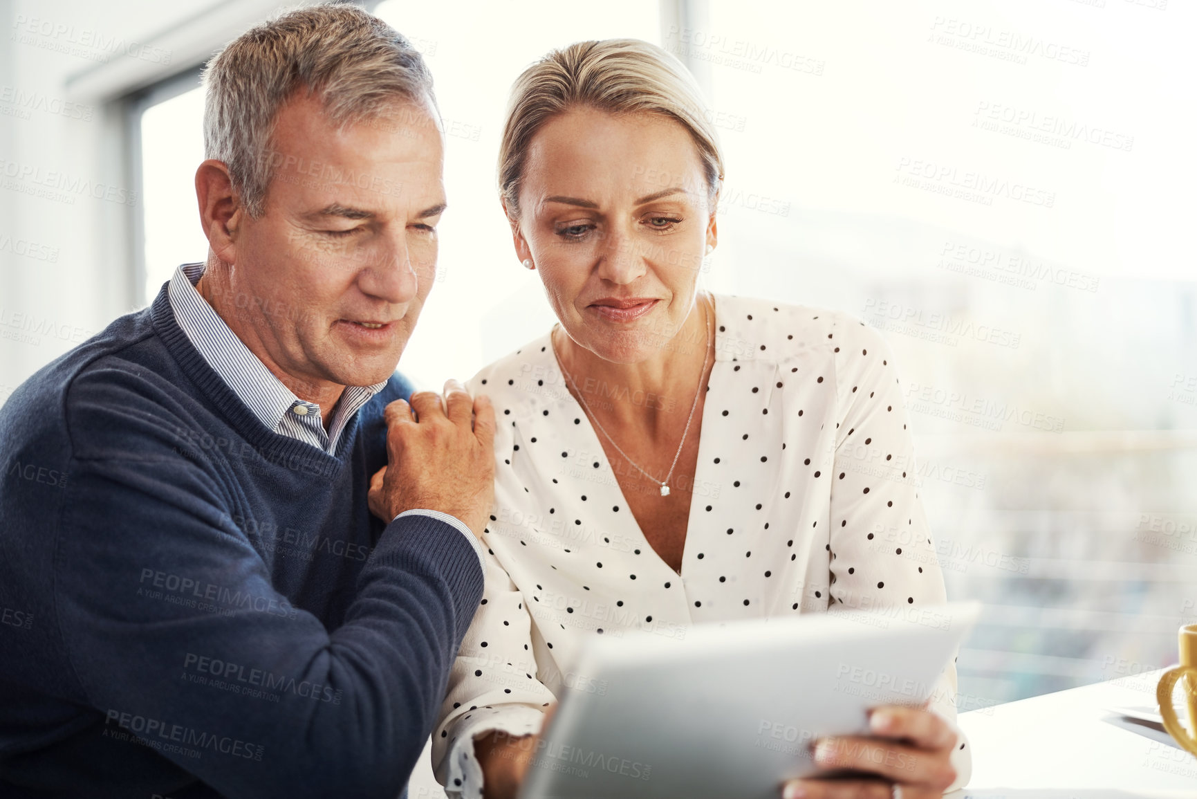 Buy stock photo Shot of a mature couple using a digital tablet together at home
