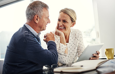 Buy stock photo Shot of a mature couple using a digital tablet while going through paperwork at home