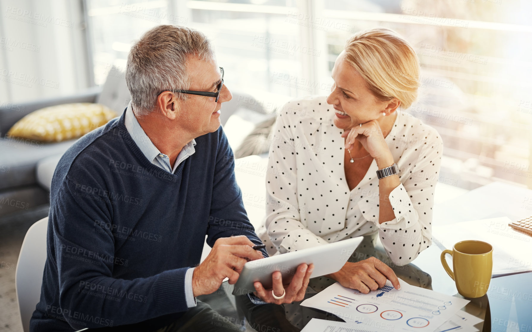 Buy stock photo Shot of a mature couple using a digital tablet while going through paperwork at home