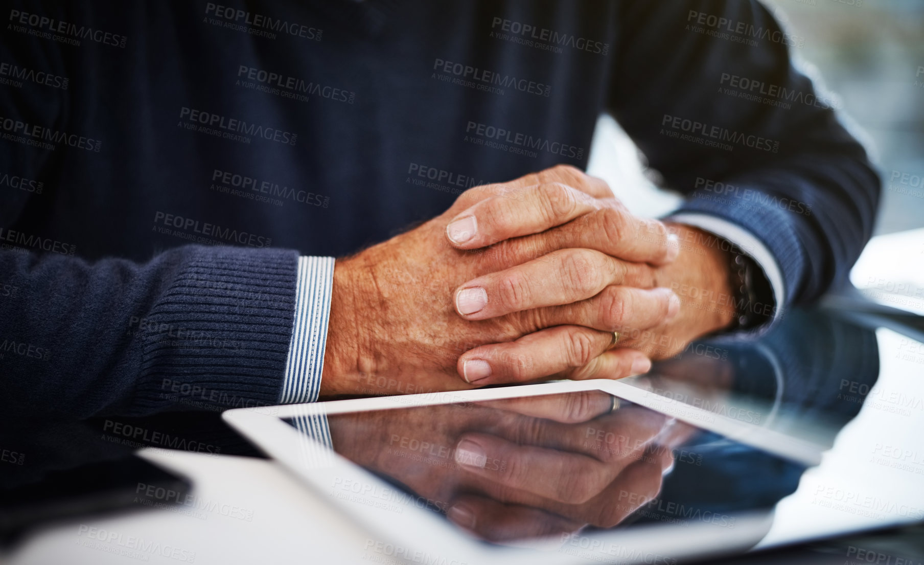 Buy stock photo Cropped shot of a businessman sitting at his work desk with his hands clasped