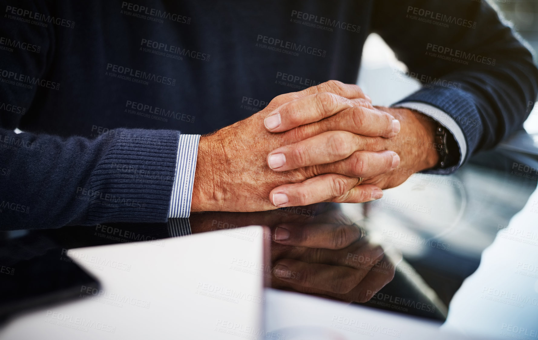 Buy stock photo Cropped shot of a businessman sitting at his work desk with his hands clasped