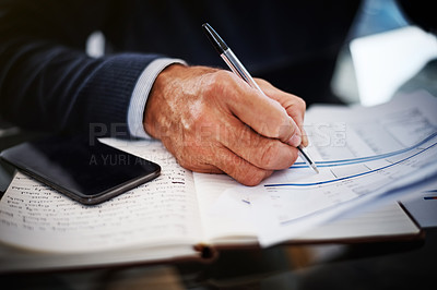 Buy stock photo Cropped shot of a businessman writing on a document at his work desk