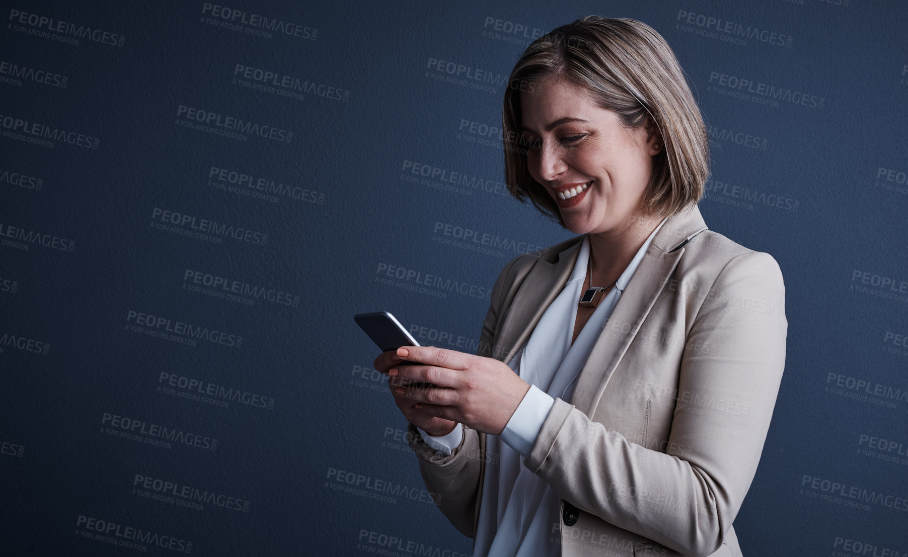 Buy stock photo Studio shot of an attractive young corporate businesswoman sending a text against a dark background