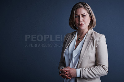 Buy stock photo Studio portrait of an attractive young corporate businesswoman posing against a dark background