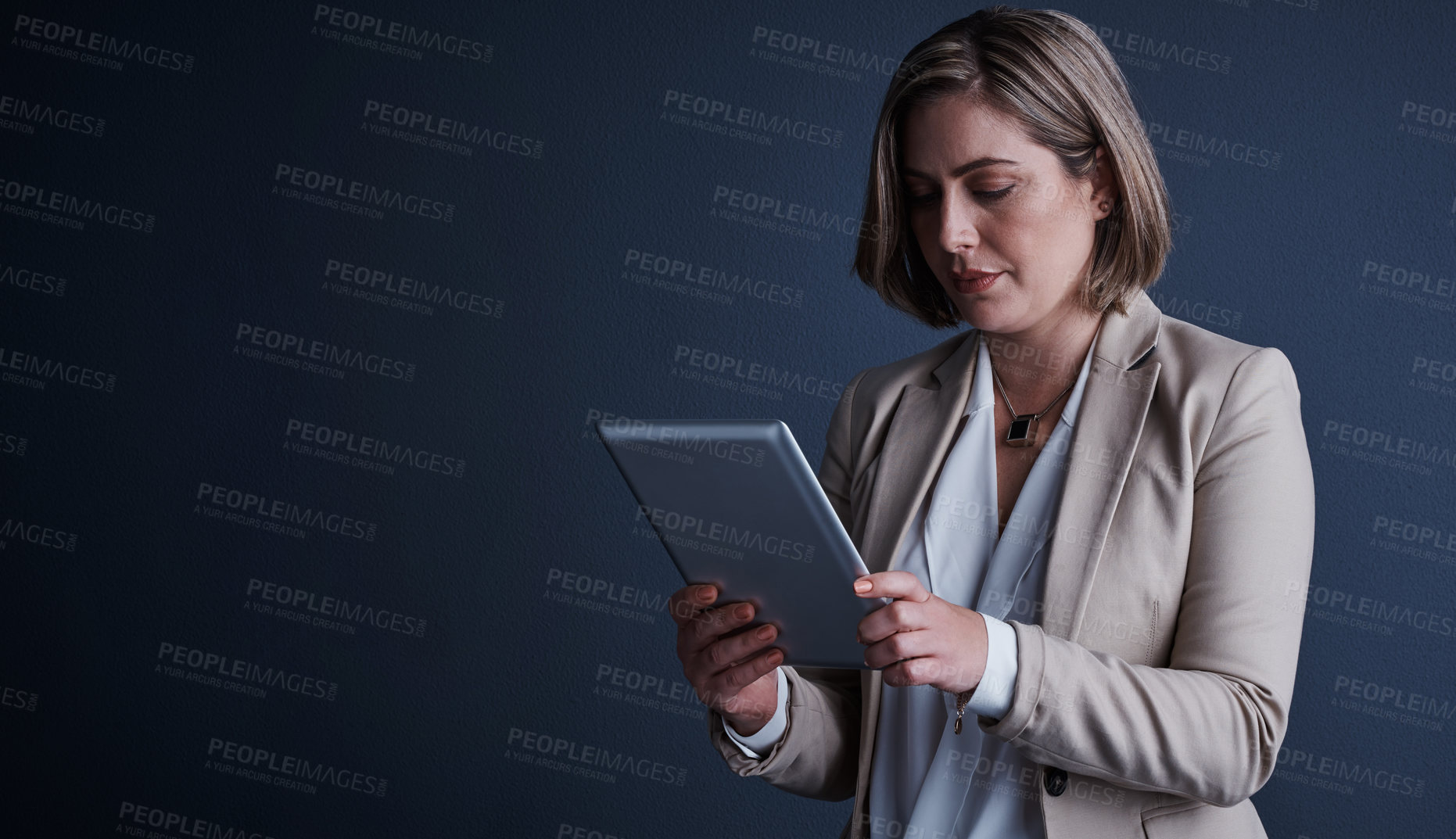 Buy stock photo Studio shot of an attractive young corporate businesswoman using a tablet against a dark background