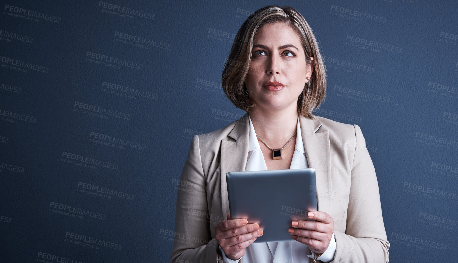 Buy stock photo Studio shot of an attractive young corporate businesswoman using a tablet against a dark background