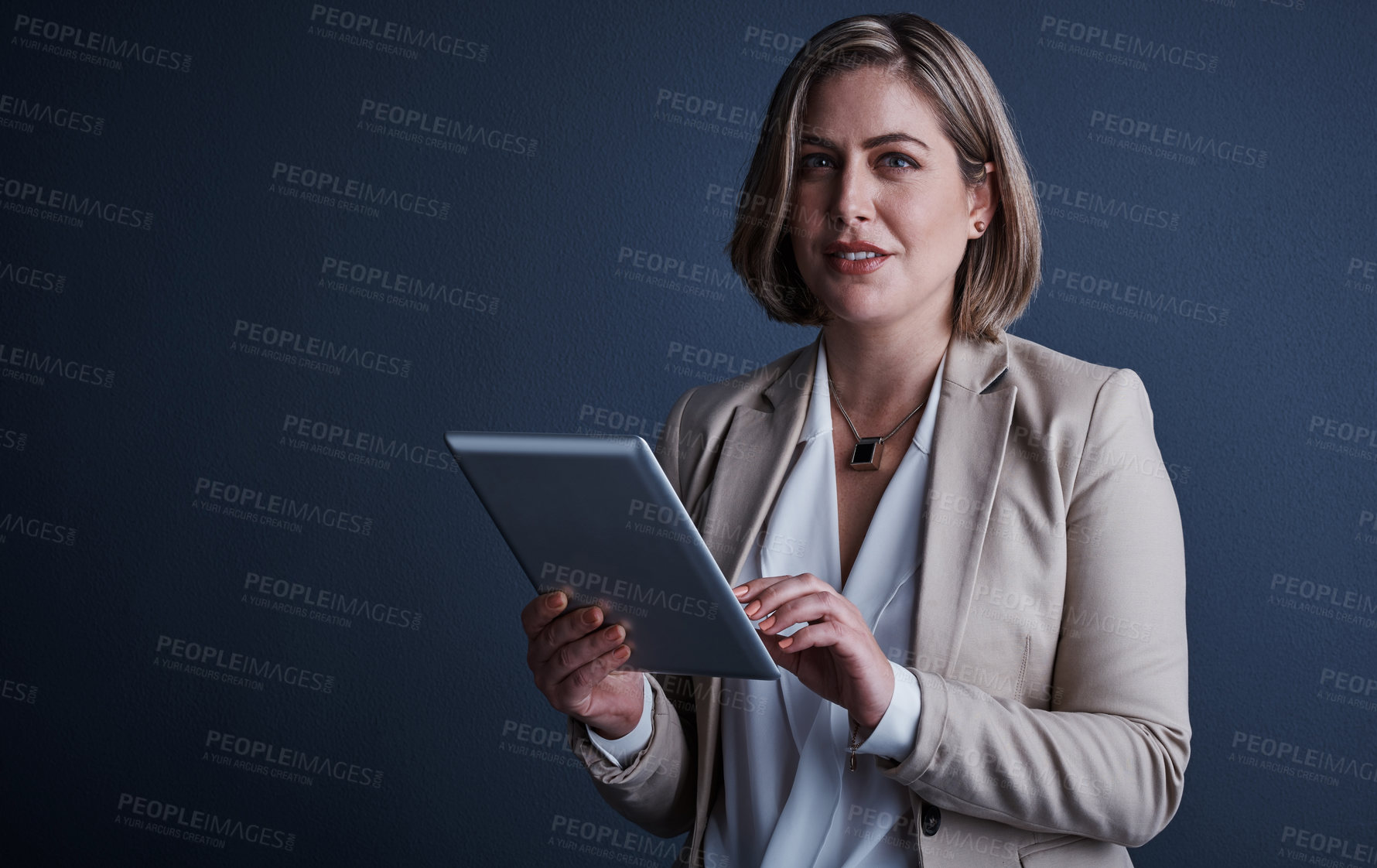 Buy stock photo Studio portrait of an attractive young corporate businesswoman using a tablet against a dark background