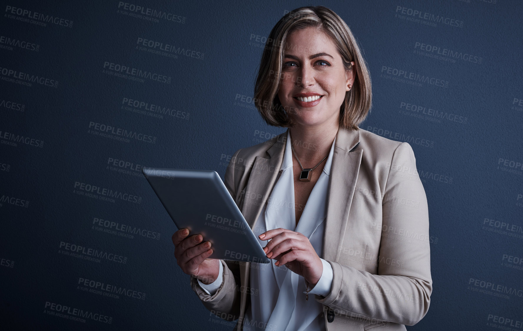 Buy stock photo Studio portrait of an attractive young corporate businesswoman using a tablet against a dark background