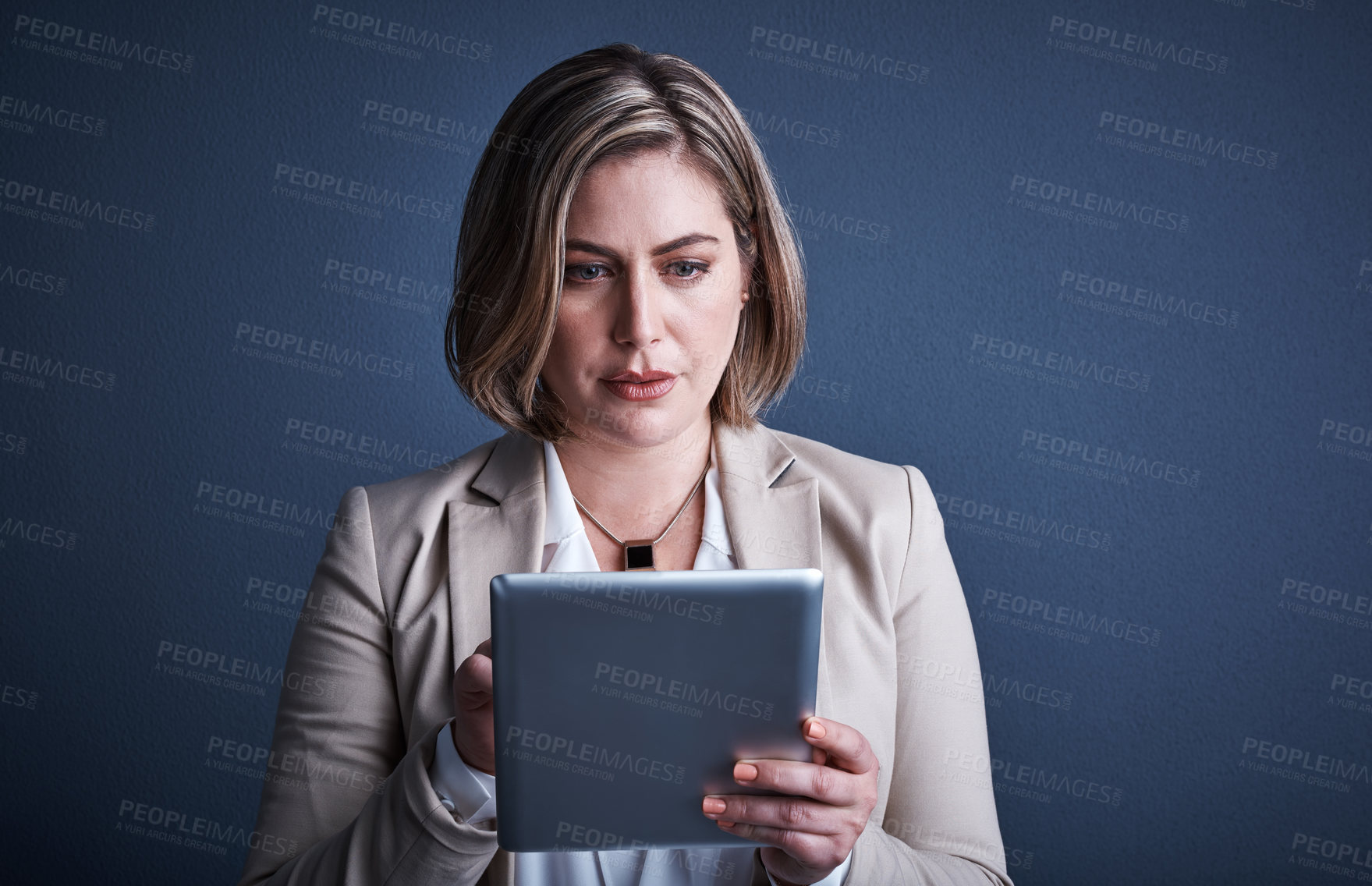 Buy stock photo Studio shot of an attractive young corporate businesswoman using a tablet against a dark background