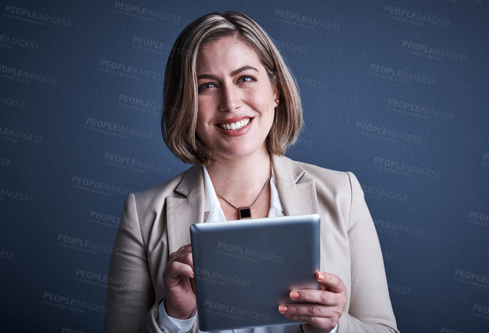 Buy stock photo Studio portrait of an attractive young corporate businesswoman using a tablet against a dark background