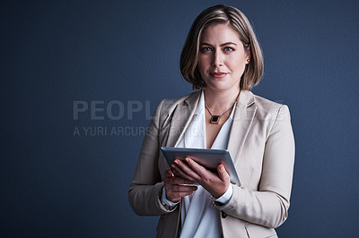 Buy stock photo Studio portrait of an attractive young corporate businesswoman using a tablet against a dark background