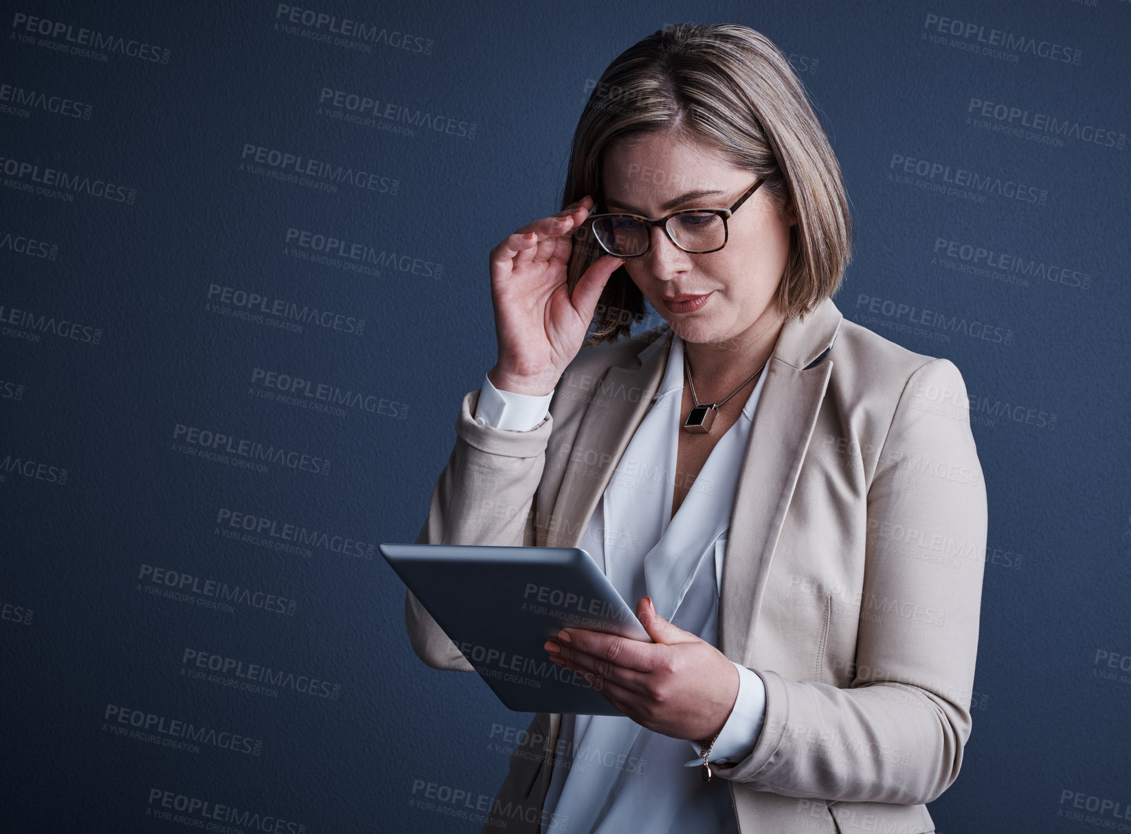 Buy stock photo Studio shot of an attractive young corporate businesswoman using a tablet against a dark background