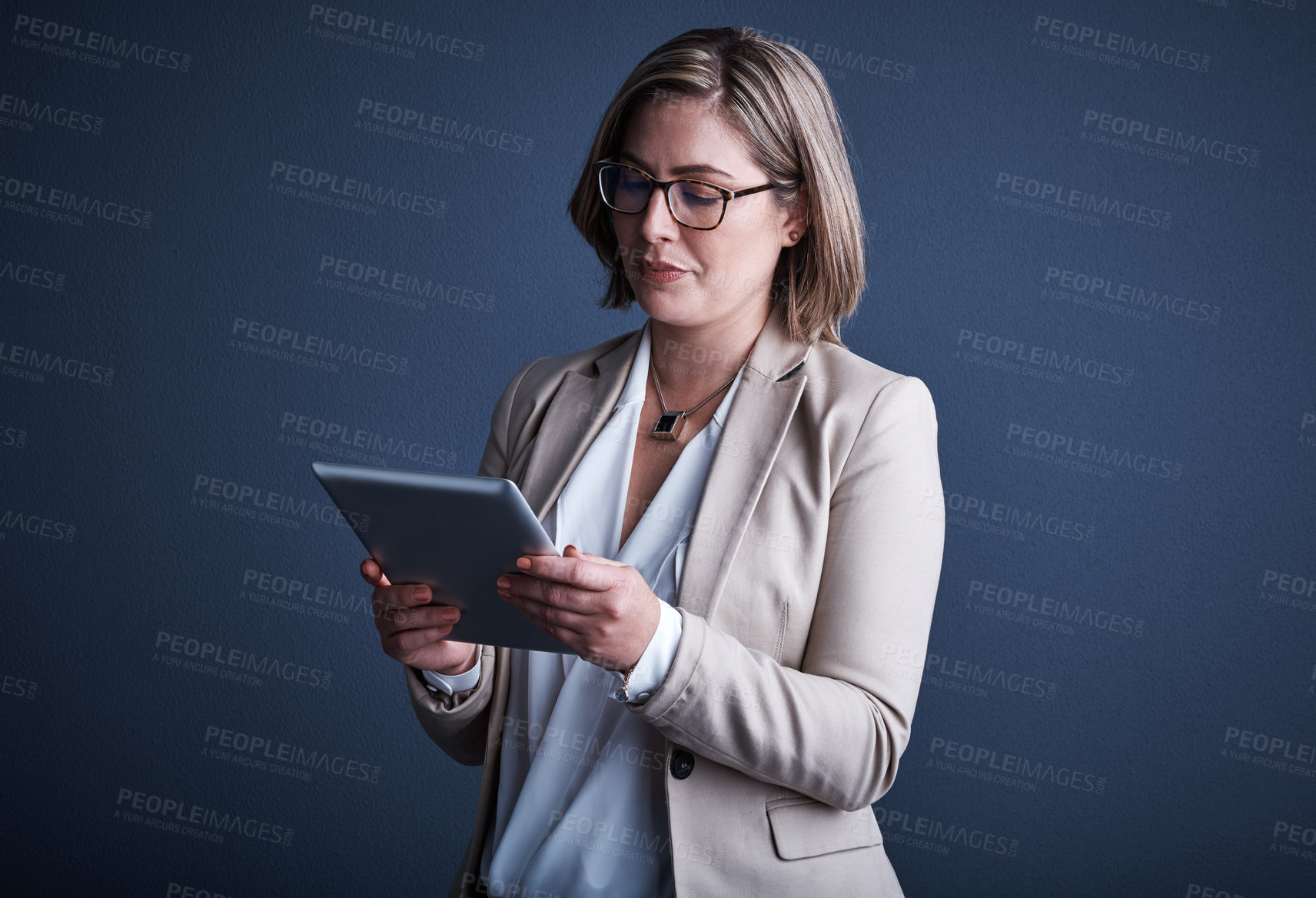 Buy stock photo Studio shot of an attractive young corporate businesswoman using a tablet against a dark background