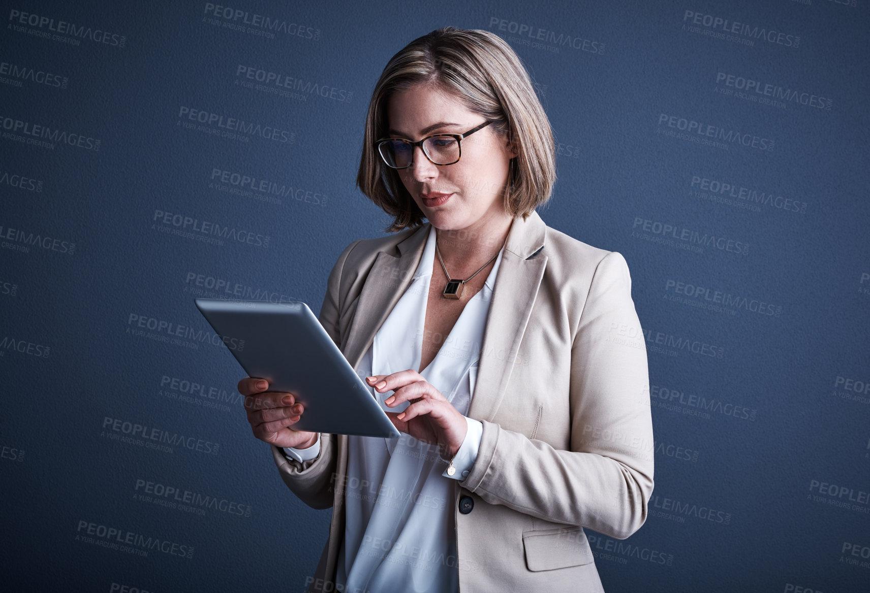 Buy stock photo Studio shot of an attractive young corporate businesswoman using a tablet against a dark background