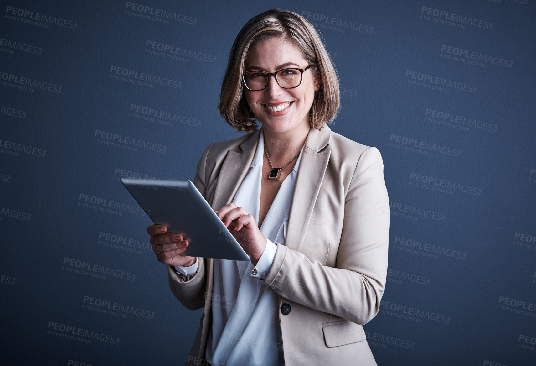 Buy stock photo Studio portrait of an attractive young corporate businesswoman using a tablet against a dark background