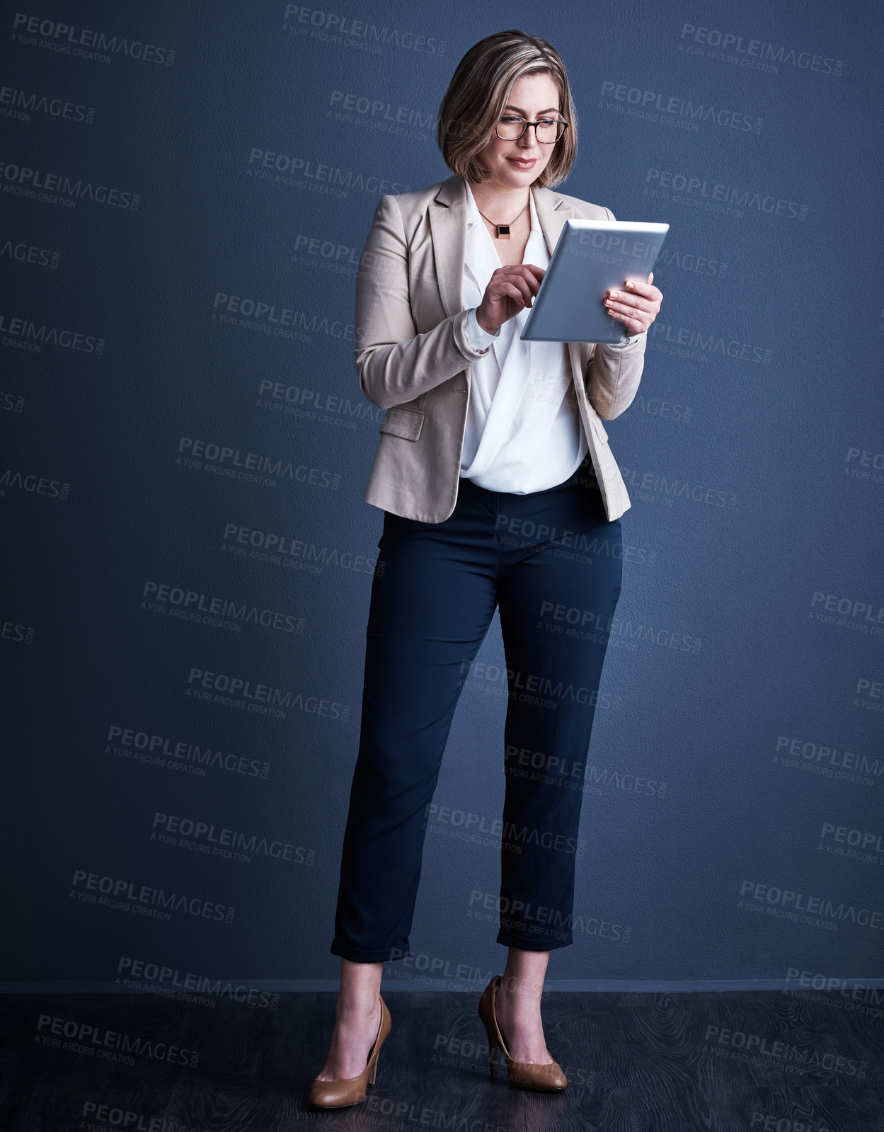 Buy stock photo Studio shot of an attractive young corporate businesswoman using a tablet against a dark background