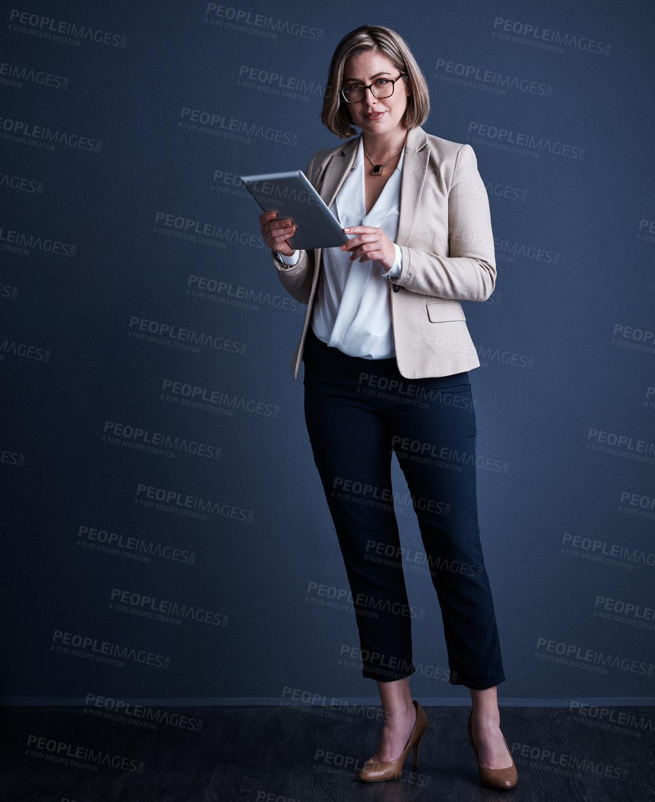 Buy stock photo Studio portrait of an attractive young corporate businesswoman using a tablet against a dark background