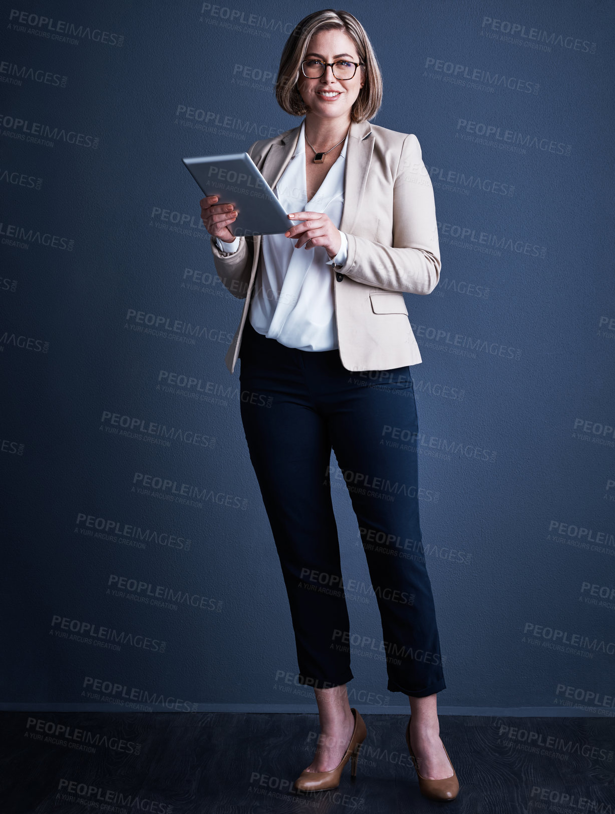 Buy stock photo Studio portrait of an attractive young corporate businesswoman using a tablet against a dark background