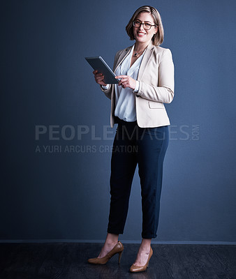 Buy stock photo Studio portrait of an attractive young corporate businesswoman using a tablet against a dark background