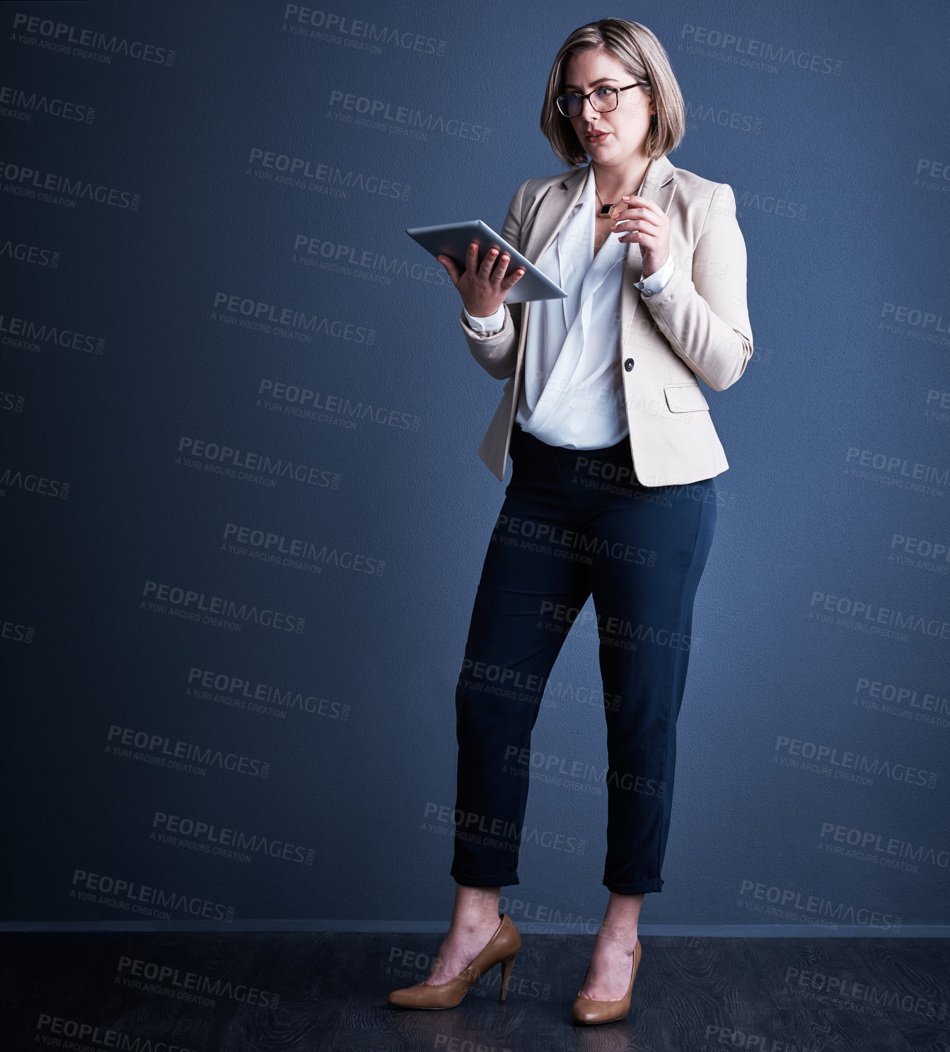 Buy stock photo Studio shot of an attractive young corporate businesswoman using a tablet against a dark background