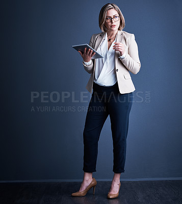 Buy stock photo Studio shot of an attractive young corporate businesswoman using a tablet against a dark background