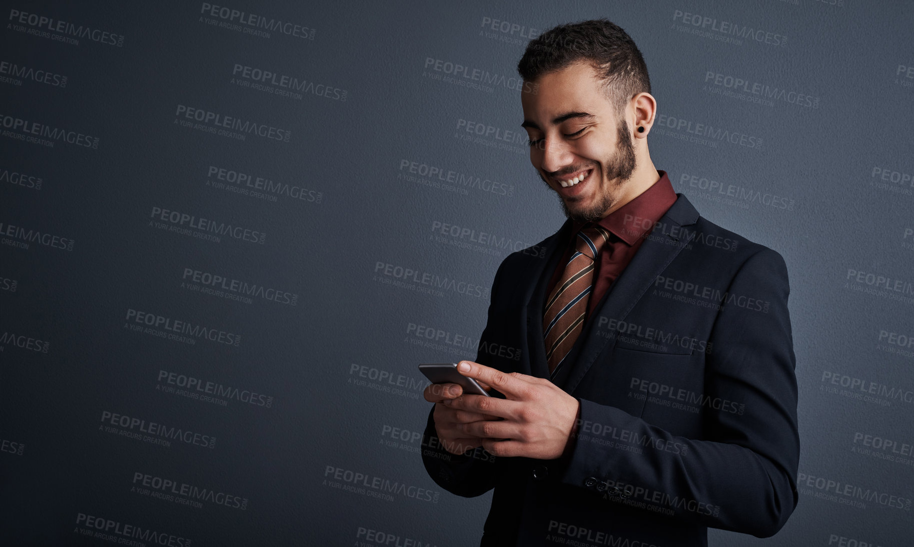 Buy stock photo Studio shot of a stylish young businessman sending a text message while standing against a gray background