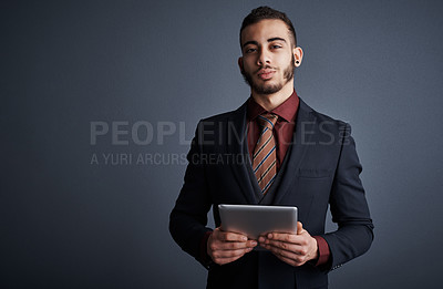 Buy stock photo Studio portrait of a stylish young businessman using a tablet against a gray background