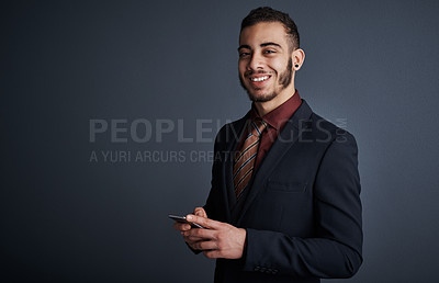 Buy stock photo Studio portrait of a stylish young businessman sending a text message while standing against a gray background