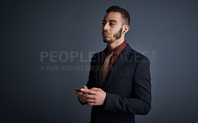 Buy stock photo Studio shot of a stylish young businessman sending a text message while standing against a gray background
