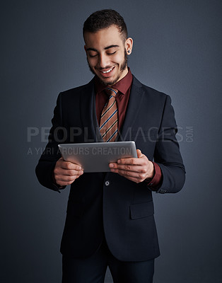 Buy stock photo Studio shot of a stylish young businessman using a tablet against a gray background