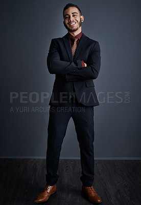 Buy stock photo Studio portrait of a stylish young businessman standing with his arms folded against a gray background