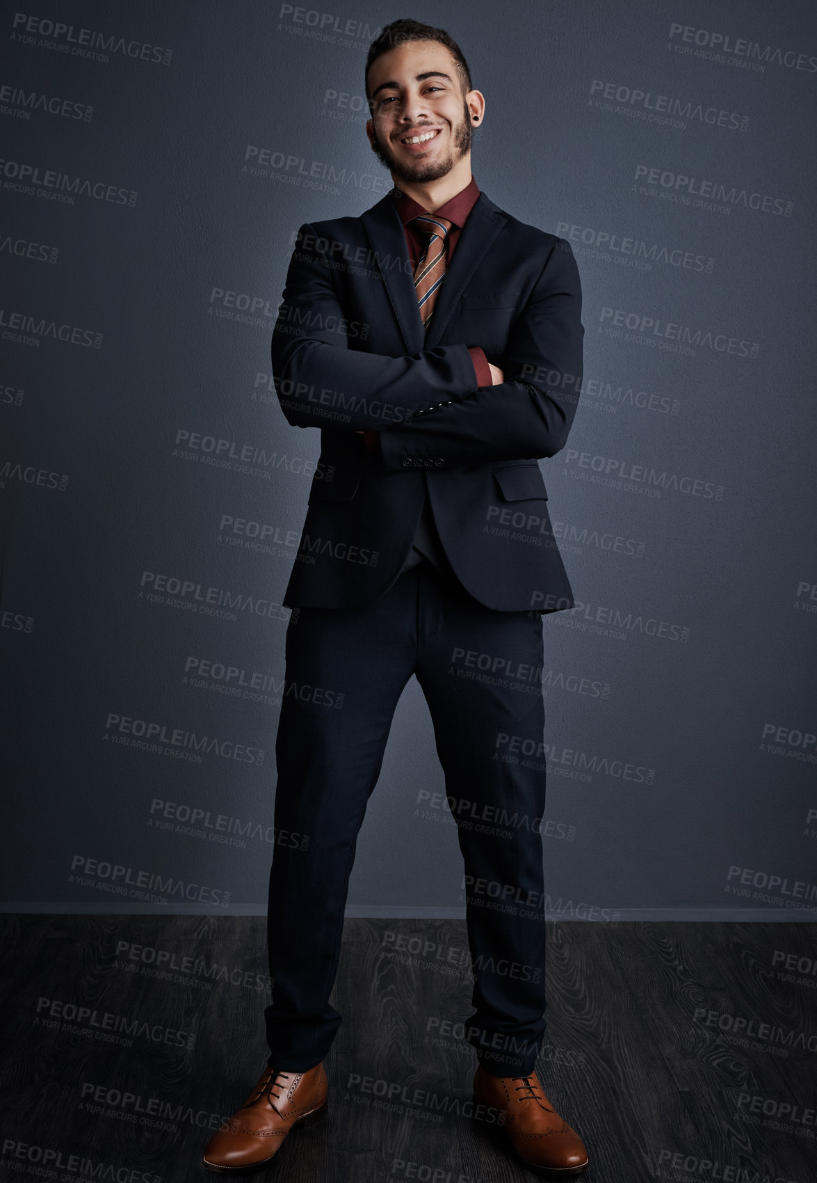 Buy stock photo Studio portrait of a stylish young businessman standing with his arms folded against a gray background