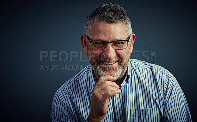 Buy stock photo Studio portrait of a confident and mature businessman sitting with his hand on his chin against a dark background