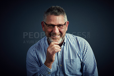 Buy stock photo Studio portrait of a confident and mature businessman sitting with his hand on his chin against a dark background