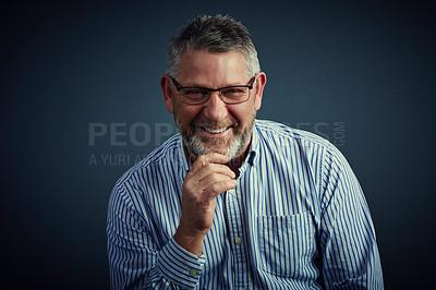Buy stock photo Studio portrait of a confident and mature businessman sitting with his hand on his chin against a dark background