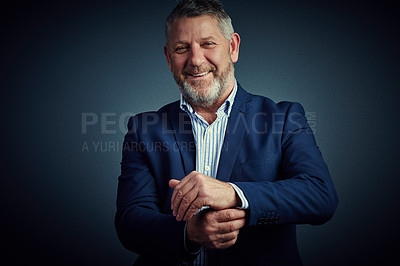 Buy stock photo Studio portrait of a confident and mature businessman buttoning his cuffs against a dark background