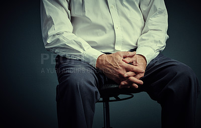 Buy stock photo Studio shot of an unrecognizable businessman sitting down against a dark background