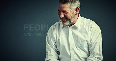 Buy stock photo Studio shot of a handsome mature businessman looking thoughtful while sitting down against a dark background