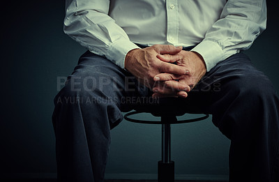 Buy stock photo Studio shot of an unrecognizable businessman sitting down against a dark background