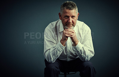 Buy stock photo Studio portrait of a handsome mature businessman looking thoughtful while sitting down against a dark background