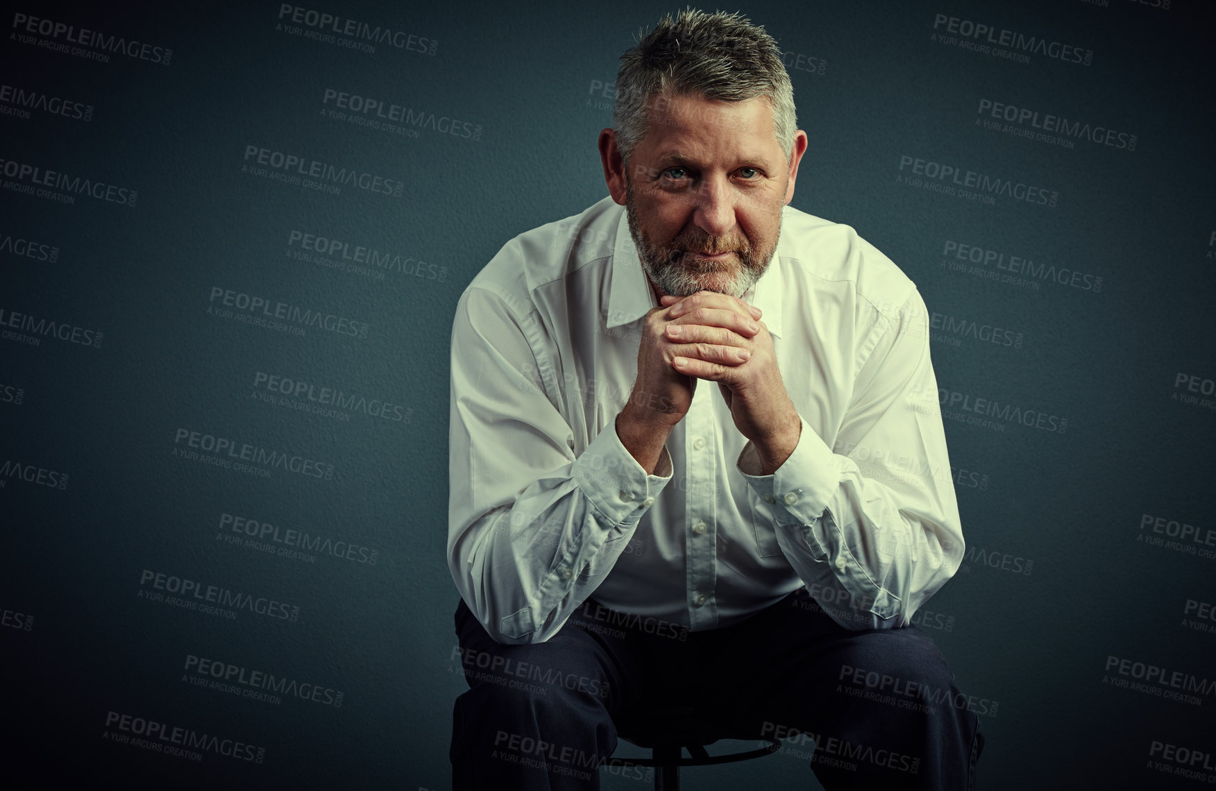 Buy stock photo Studio portrait of a handsome mature businessman looking thoughtful while sitting down against a dark background