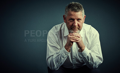 Buy stock photo Studio portrait of a handsome mature businessman looking thoughtful while sitting down against a dark background