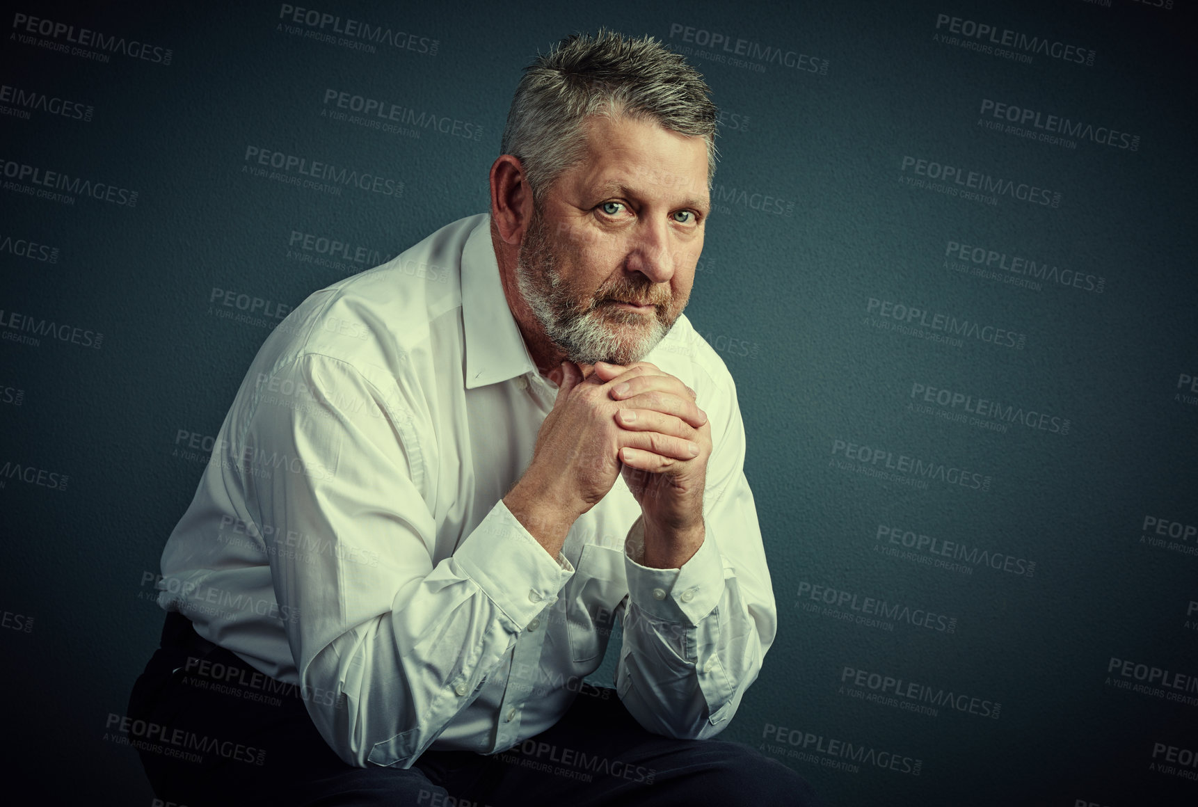 Buy stock photo Studio portrait of a handsome mature businessman looking thoughtful while sitting down against a dark background