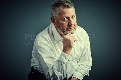 Buy stock photo Studio portrait of a handsome mature businessman looking thoughtful while sitting down against a dark background